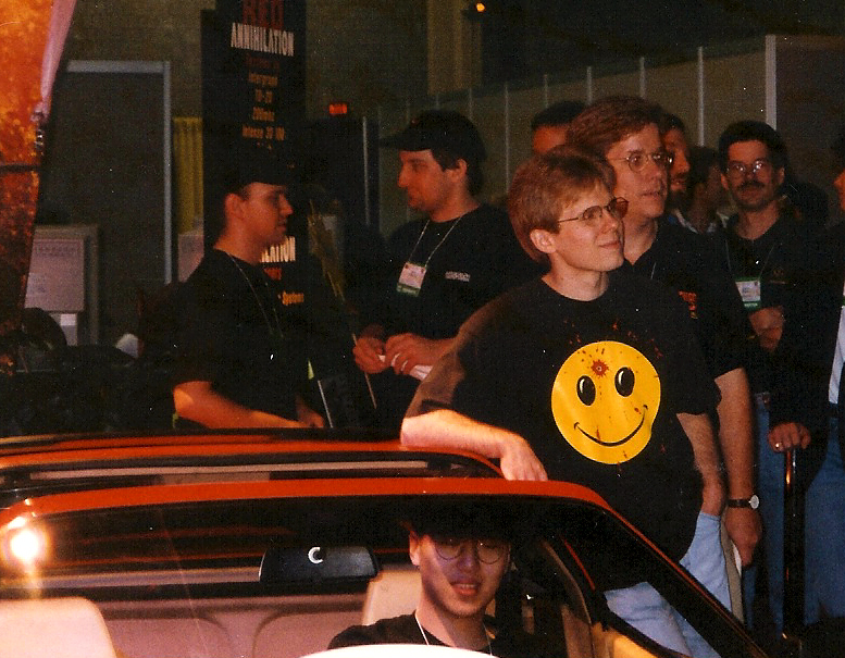 John Carmack leaning on a red Ferrari; Dennis Fong, who won it, sits in the driver’s seat